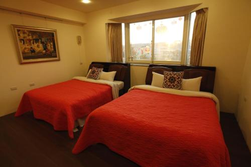 新社區的住宿－花田民宿，客房设有两张带红色床单的床和窗户。