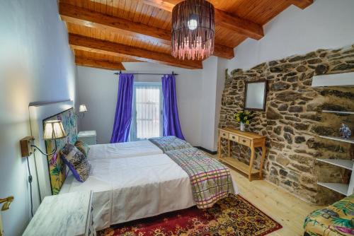 1 dormitorio con cama y pared de piedra en casa do peso, en Monforte de Lemos