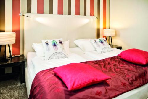 a bed with red and white pillows on it at City Hotel Bosse in Bad Oeynhausen