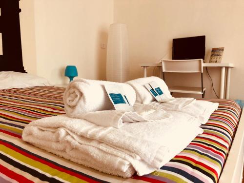 Castelnuovo Rooms في باليرمو: غرفة نوم مع مناشف بيضاء على سرير