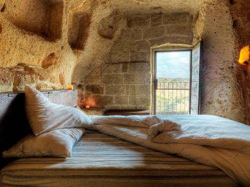 a large bed in a room with a window at Sextantio Le Grotte Della Civita in Matera