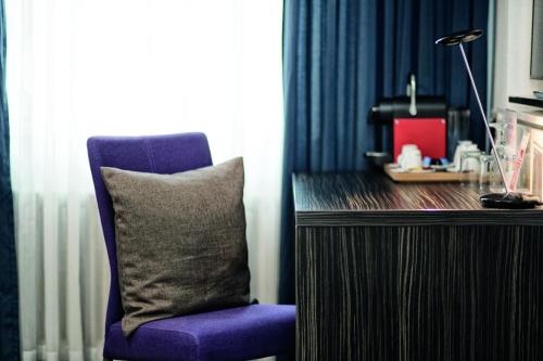 a purple chair sitting next to a desk with a pillow at City Hotel Bosse in Bad Oeynhausen