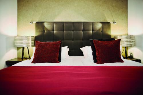 a bedroom with a large bed with two red pillows at City Hotel Bosse in Bad Oeynhausen