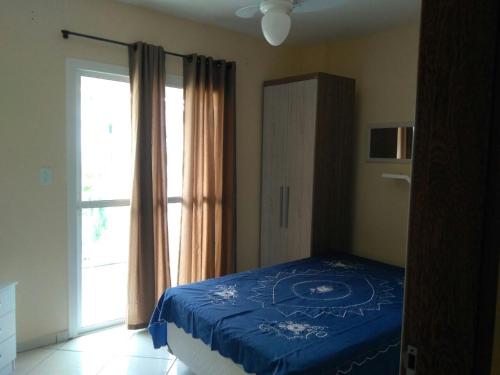 Un dormitorio con una cama azul y una gran ventana. en Aconchego no Paraíso, en Arraial do Cabo