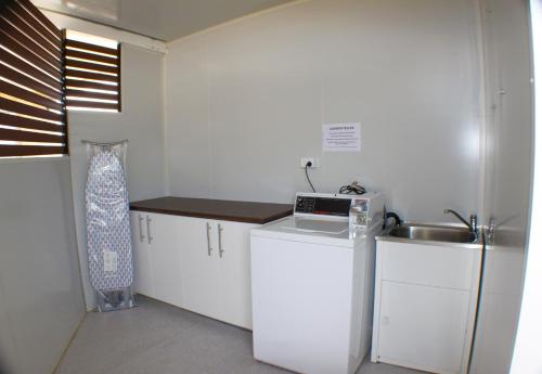 a small white kitchen with a sink and a microwave at Baths Motel Moree in Moree