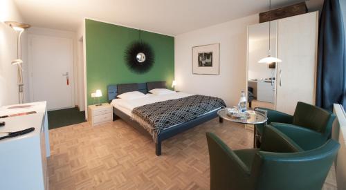 1 dormitorio con cama y pared verde en Le Mont-Vully - Hôtel Restaurant, en Haut-Vully