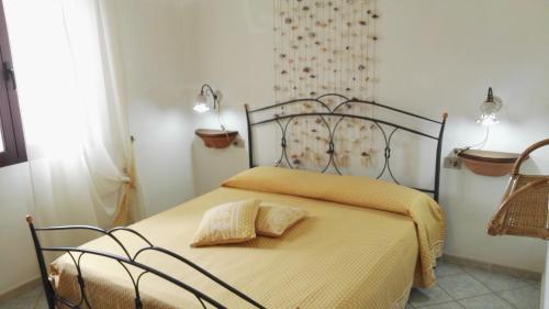 a bed with a yellow blanket and two pillows on it at Appartamenti Sardegna in Porto San Paolo