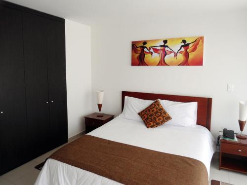 a bedroom with a bed and a painting on the wall at 122 Plaza Apartahotel in Bogotá