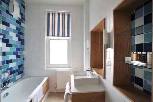 a bathroom with a tub and a sink and a window at The Brudenell in Aldeburgh