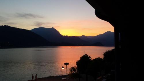 a sunset over a lake with mountains in the background at Foresteria Lombarda La Spiaggia in Lierna