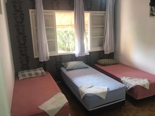 two twin beds in a room with a window at Pousada Hostel Universitário in Londrina