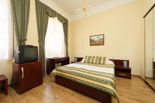 a bedroom with a bed and a tv in it at Hotel Blaha Lujza in Balatonfüred