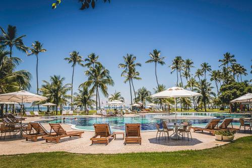 a resort pool with chairs and tables and palm trees at Patachocas in Morro de São Paulo