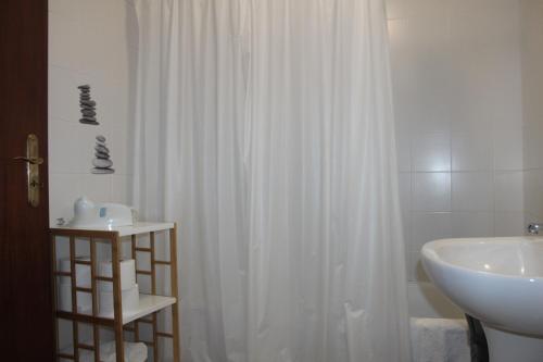 uma casa de banho com uma cortina de chuveiro branca e um lavatório. em ApartAnita em Ponta Delgada