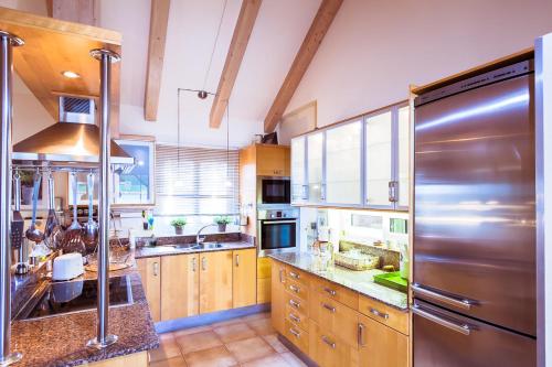 een keuken met houten kasten en een roestvrijstalen koelkast bij Villa Hibiscus Centrum Corralejo Beach Private Pool Family in Corralejo