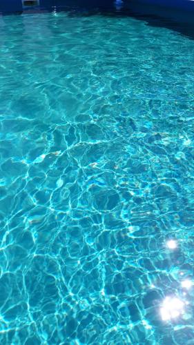 una piscina de agua azul con luz reflejada en el Alfil Apartamentos Villa Gesell en Villa Gesell