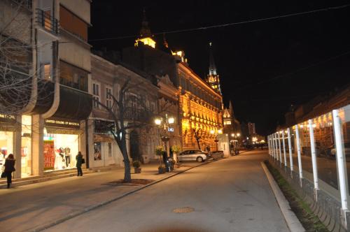 a city street at night with a building with a clock tower at Apartment Eugen in Novi Sad