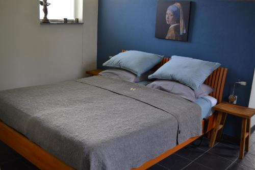 een bed in een kamer met een blauwe muur bij Appartement De Bosuil in Groesbeek