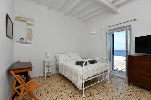 1 dormitorio con 1 cama y TV y el océano en Kastro Traditional House, en Parikia