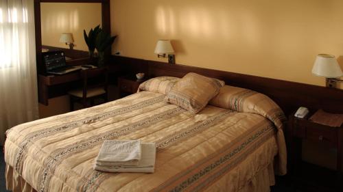 ein Hotelzimmer mit einem Bett mit einem Buch darauf in der Unterkunft Hotel Centro in San José de Mayo