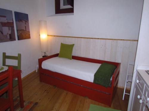 a small bedroom with a bed with green pillows at Casa da Rua Nova in Castelo de Vide