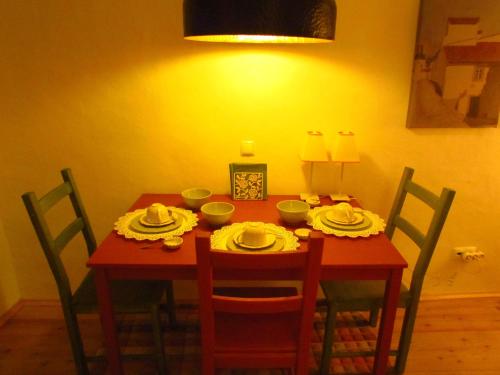 a dining room table with chairs and a red table with yellow walls at Casa da Rua Nova in Castelo de Vide