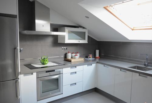 a kitchen with white cabinets and a skylight at Apartamento Vila O Valadouro in Ferreira