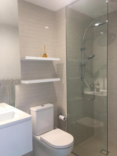a bathroom with a toilet and a glass shower at Panoramic views in luxurious brand new apartment in Sydney