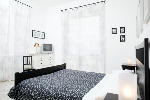 a white bedroom with a bed and a tv at Il Vicolo B&B in Milazzo