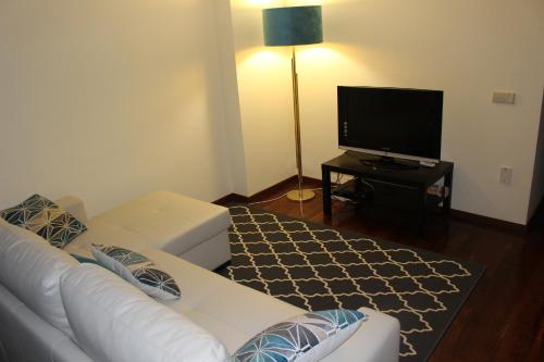a living room with a white couch and a flat screen tv at Apartamento Latino Coelho in Póvoa de Varzim