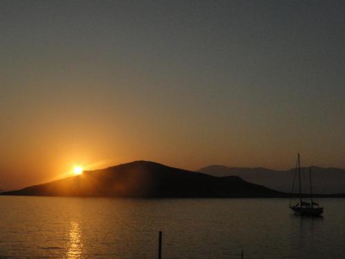 a boat in the water in front of a sunset at Cohili Villa in Halki