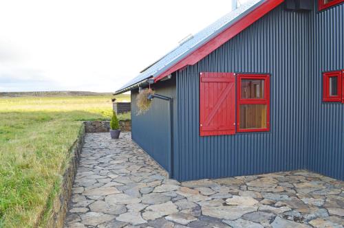 a blue building with a red door and a window at Laugarfell Accommodation & Hot Springs in Laugarfell