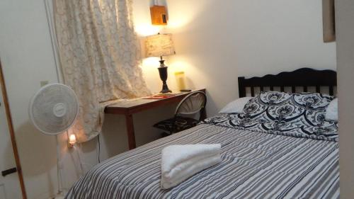 a bedroom with a bed with a fan and a lamp at Hacienda Tropical Guest House in Belmopan