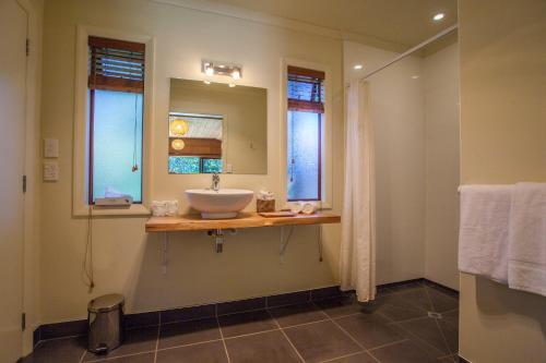 uma casa de banho com um lavatório e 2 janelas em The Rocks Chalets em Takaka
