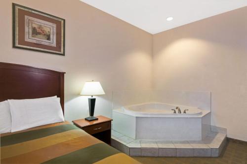 um quarto de hotel com uma cama e uma banheira em Super 8 by Wyndham Austin/Airport South em Austin