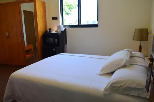 a bedroom with a bed with white sheets and a window at Saipan Beach Hotel in Saipan