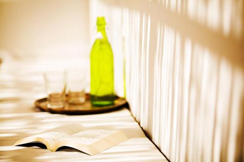 a book and a bottle on a table next to a window at Il Vicolo B&B in Milazzo