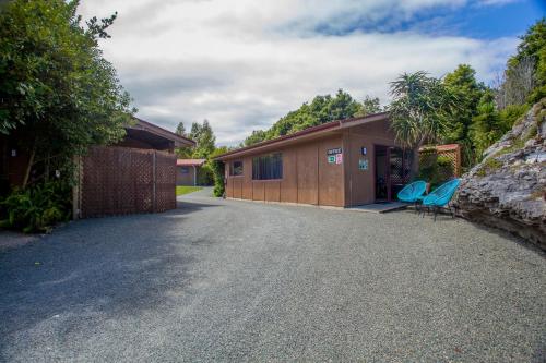 a building with two blue chairs in the driveway at The Rocks Chalets in Takaka