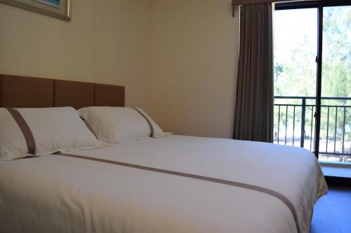 a bedroom with a large white bed with a window at Saipan Beach Hotel in Saipan