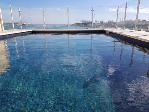 a swimming pool with blue water in a building at Fisherman's Cove Guesthouse in Marsaxlokk