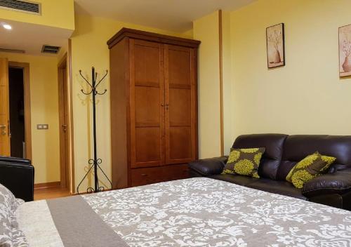a bedroom with a bed and a leather couch at Hotel Reina Isabel in Medina del Campo