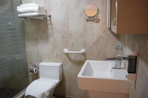 a bathroom with a white toilet and a sink at Saipan Beach Hotel in Saipan