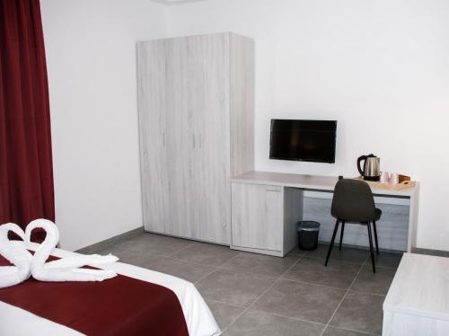 a bedroom with a bed and a desk with a television at Fisherman's Cove Guesthouse in Marsaxlokk