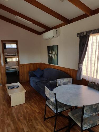 a living room with a blue couch and a table at Koonwarra Holiday Park in Lakes Entrance