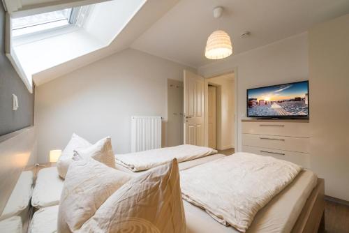 2 Betten in einem Schlafzimmer mit einem TV an der Wand in der Unterkunft Altstadt Wohnung 5 "Langeneß" in Borkum