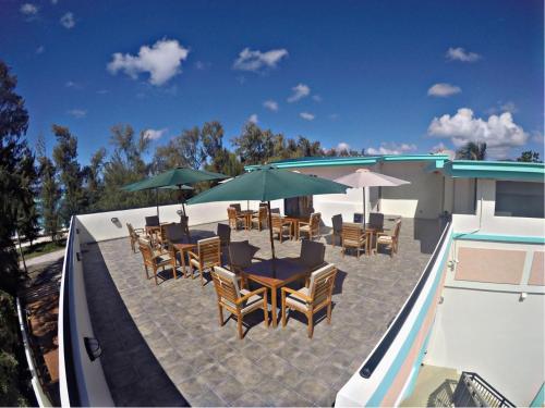 a patio with tables and chairs with umbrellas and a pool at Saipan Beach Hotel in Saipan