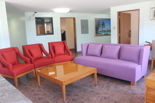 a living room with a purple couch and red chairs at Saipan Beach Hotel in Saipan