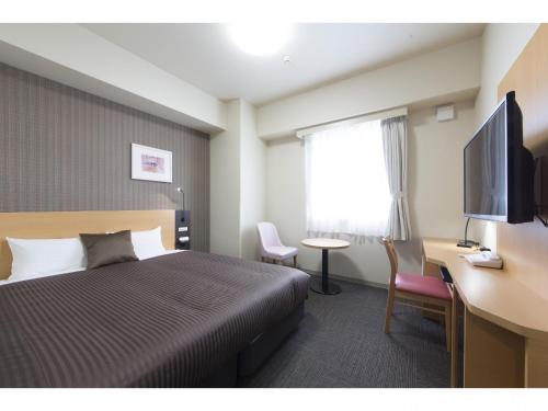 a hotel room with a bed and a desk and a television at Hotel Super Tomari in Fujieda