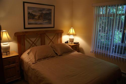 a bedroom with a bed with two lamps and a window at Whistler Superior Properties in Whistler