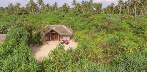 two people sitting in front of a hut at Jungle Beach Ahungalla in Ahungalla